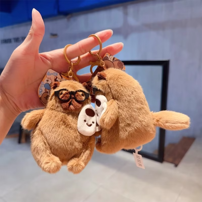 This dangling keychain in the shape of a capybara, with a plush body and bag that is wadded and fluffy, is a cool and whimsical accessory in the Wag Tail Soft Animal Keychain - Image 2
