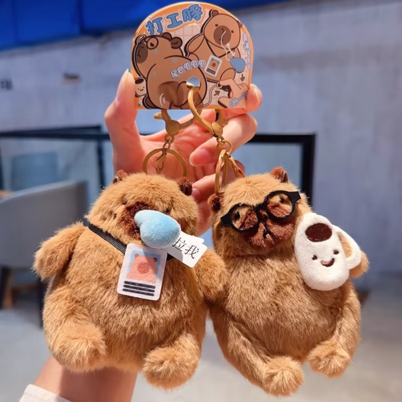 This dangling keychain in the shape of a capybara, with a plush body and bag that is wadded and fluffy, is a cool and whimsical accessory in the Wag Tail Soft Animal Keychain